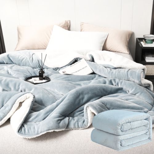 Svijetloplava deka od mikrovlakna s krznom na krevetu