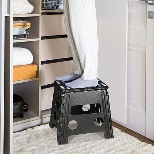 Osoba stoji na crnoj sklopivoj stepenici u pidžami ispred ormara u spavaćoj sobi