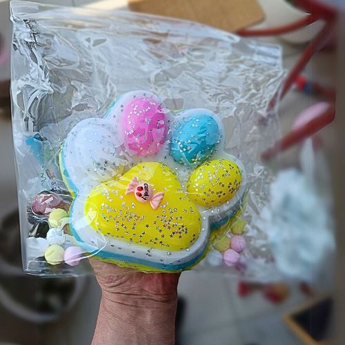 Antistres silikonska mačja šapa u ruci, zapakirana u prozirnu vrećicu s vidljivim šarenim kuglicama