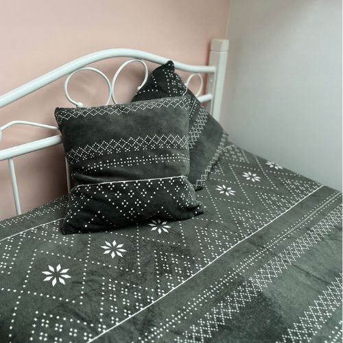 Zimski set s dekom i jastučnicama na bijelom metalnom krevetu, tamno siva podloga s bijelim božićnim uzorkom